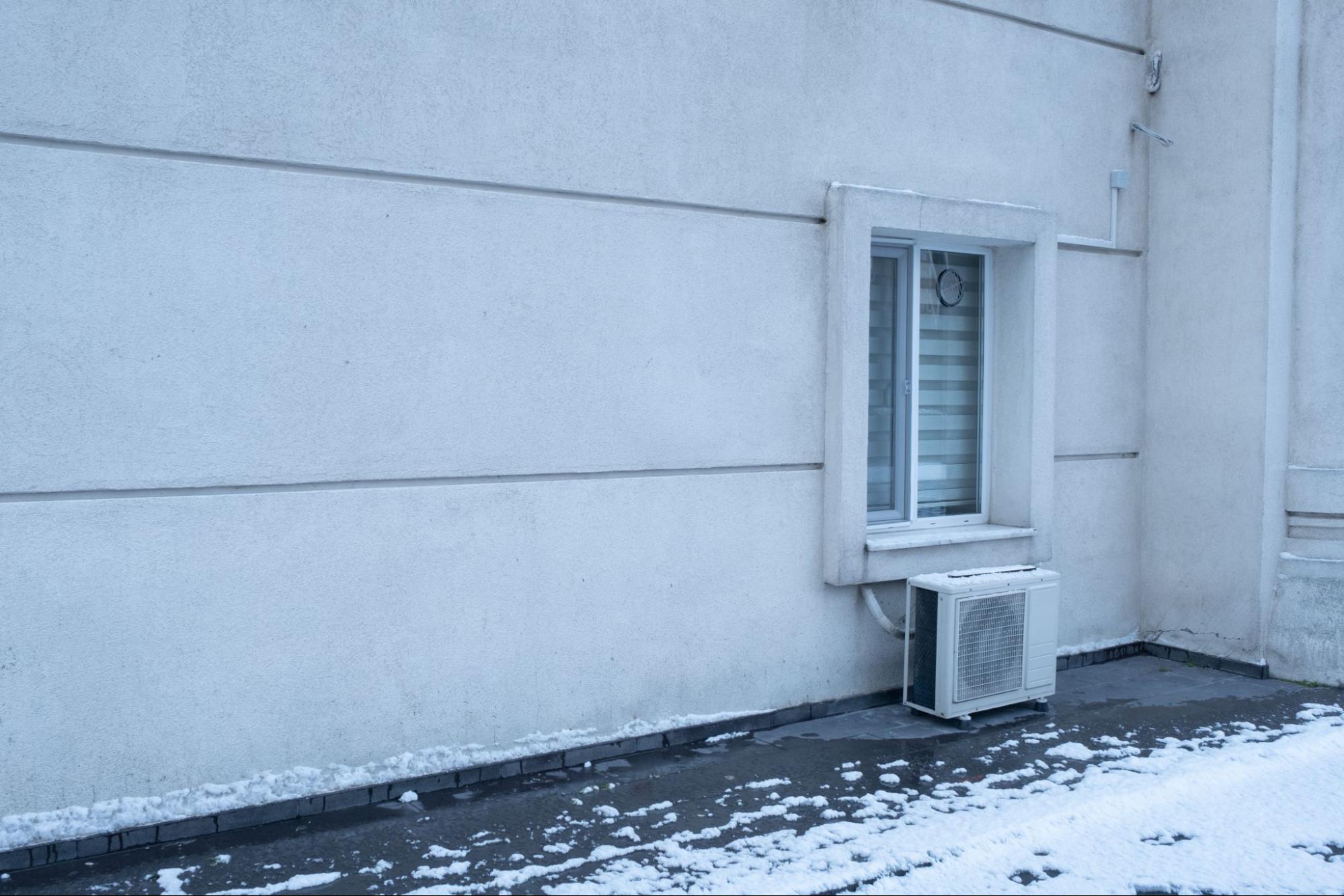 Detailný pohľad na vonkajší modul split klimatizácie pripevnený ku stene domu